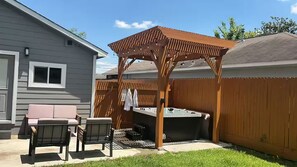 Ein Garten mit einer Holz-Pergola, einem Whirlpool und Gartenmöbeln.