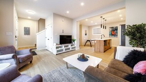 A modern living room with a flat-screen TV, a coffee table, and two sofas.