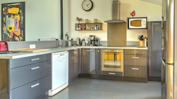 Una cocina moderna con electrodomésticos de acero inoxidable, lavavajillas y microondas.