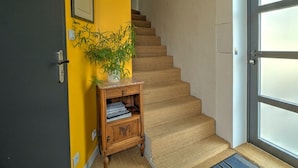 Una escalera con detalles de madera, una pared amarilla con un cuadro enmarcado, y una puerta con paneles de vidrio esmerilado.