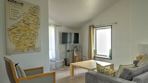 Una sala de estar con un sofá, una mesa de centro de madera, un mapa en la pared y un televisor montado sobre un mueble de madera.