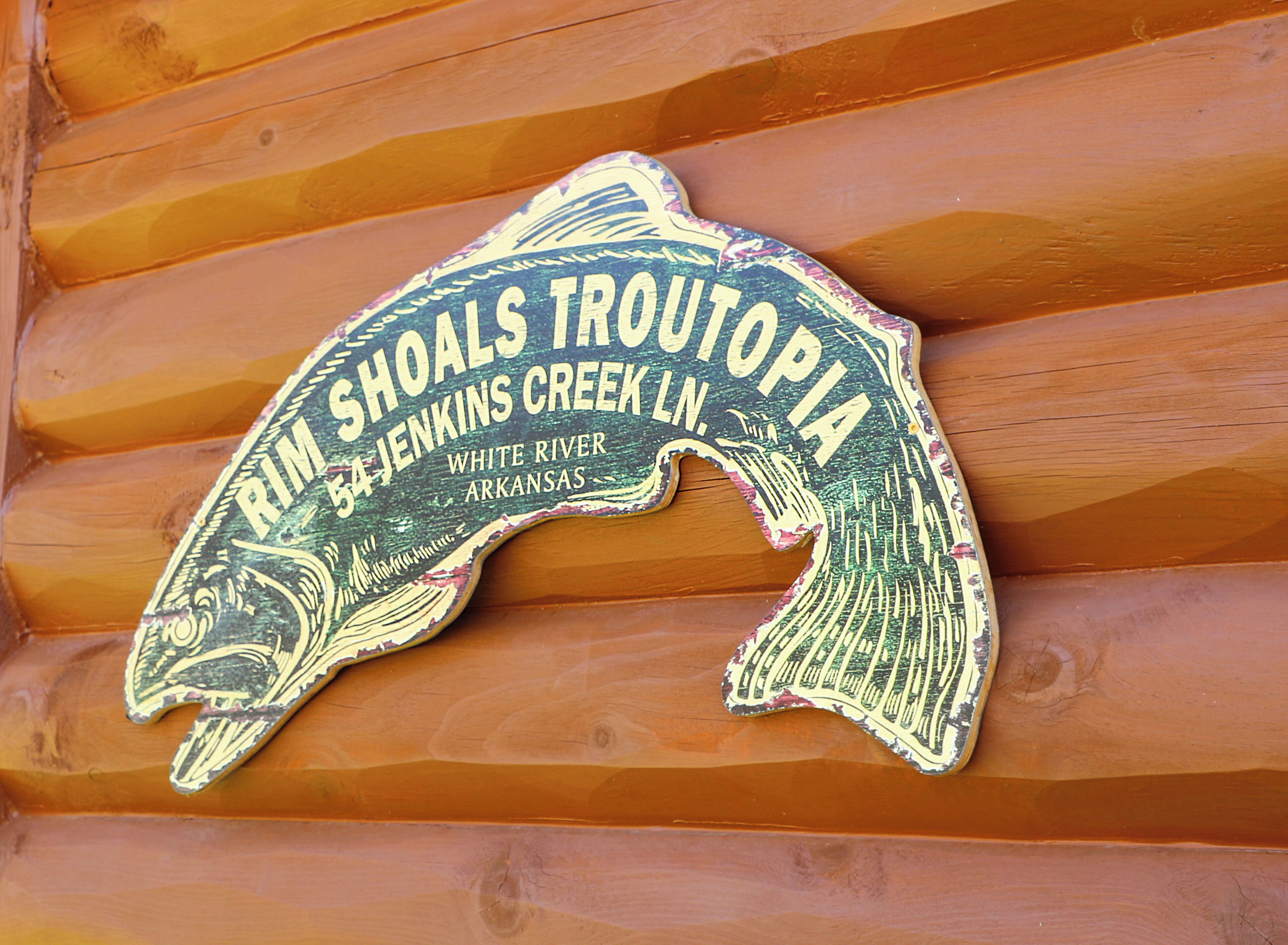 A wooden sign with text and a fish illustration.