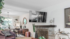 Un salon moderne doté d’une cheminée, d’un téléviseur et d’un coin repas avec un bar mobile.