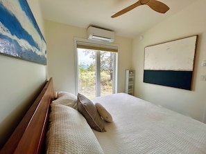 A bedroom with a bed, pillows, an air conditioning unit, a ceiling fan, a window, and a view of the outdoors. - Osoyoos Lake View | 2BR Hot Tub Retreat (Osoyoos)