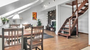 Un loft moderne avec une table à manger en bois, des chaises, un escalier et une bibliothèque.