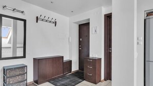 Un intérieur moderne avec un meuble en bois foncé, un miroir, une porte et un sol carrelé.