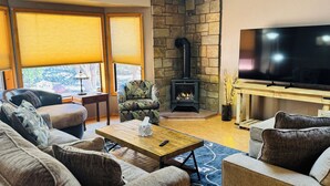 A cozy living room with a stone fireplace, comfortable seating, and a flat-screen TV. - Charming 3-bedroom house with WiFi, fitness/gameroom in Sedona! Serene Backyard! (Sedona)
