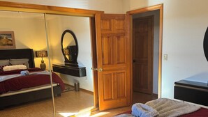 A bedroom with a bed, a mirror, a dresser, and a door. - Charming 3-bedroom house with WiFi, fitness/gameroom in Sedona! Serene Backyard! (Sedona)