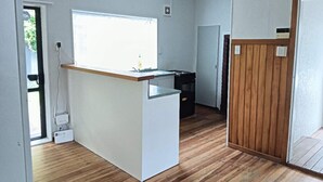Een compacte keuken met een houten aanrecht, een raam en een deur naar een andere kamer.