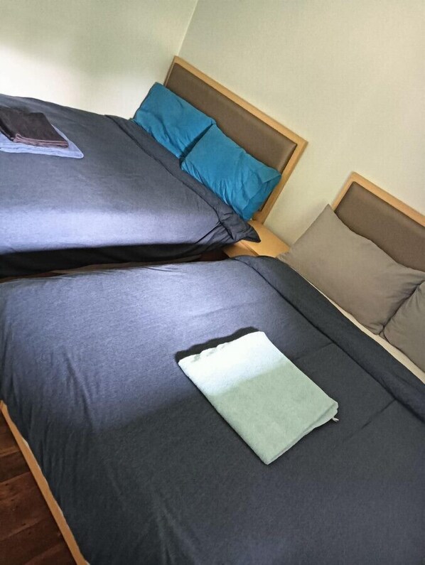 A bed with grey bedding and two pillows, one blue and one beige. - 5 Bedroom House at 7 Salisbury Road (Rotorua)