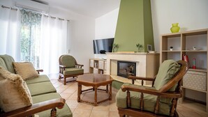 A living room with a fireplace, green sofas, wooden chairs, a coffee table, and a TV. - G&A Family Home near the Beach by MΡS (Nea Makri)