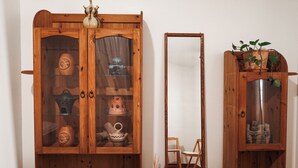 A wooden cabinet with glass doors displaying pottery and a mirror cabinet with a plant. - Rustic Casona w. Seaview, Fire Pit & AC between Cabo Rojo & Lajas (Cabo Rojo)