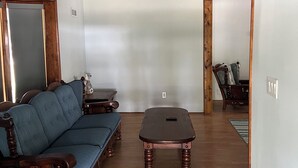 Une pièce avec un canapé en bois, une petite table en bois et un sol carrelé.