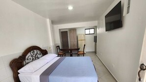 Ein Schlafzimmer mit einem Bett, einem Schreibtisch und einem an der Wand befestigten Fernseher.