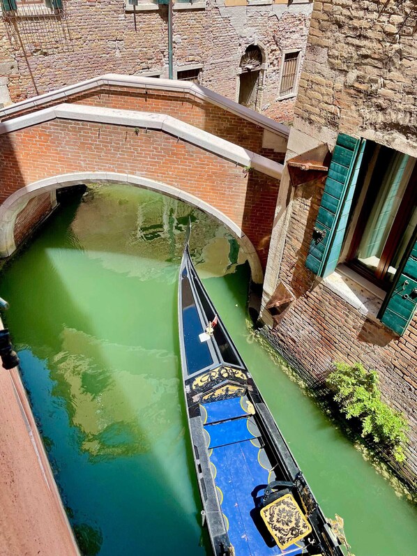 Un canal étroit, un bateau, un pont en briques et un bâtiment avec une fenêtre.