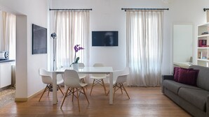 A modern living room with a dining table, chairs, a sofa, and a TV. - Vintage Style Apartment next to Fenice Theatre (Venecia)