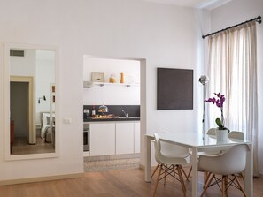 A modern kitchen with white cabinets, a dining table with chairs, and a potted orchid. - Vintage Style Apartment next to Fenice Theatre (Venecia)