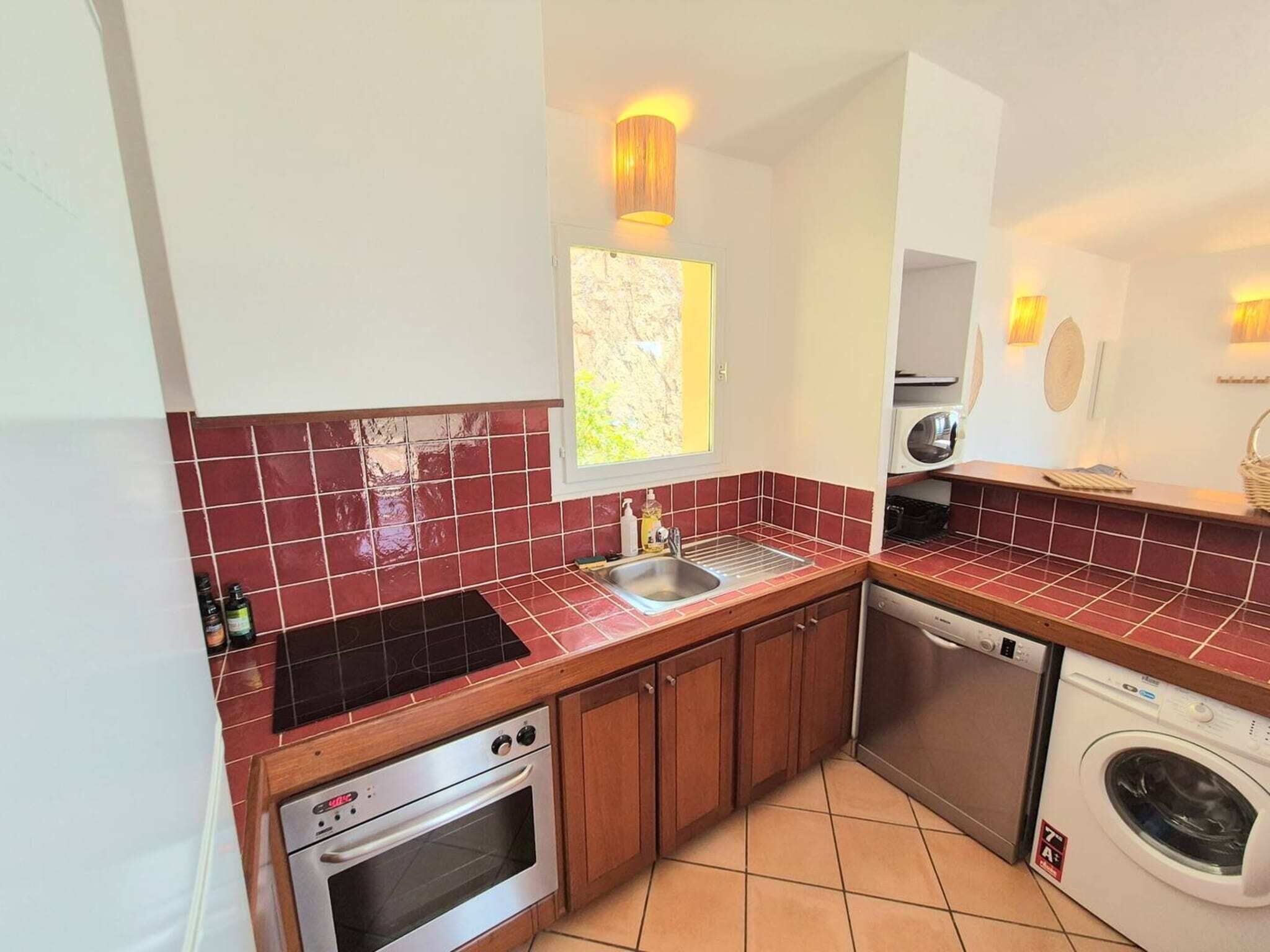 A compact kitchen with a stove, oven, sink, and washing machine.