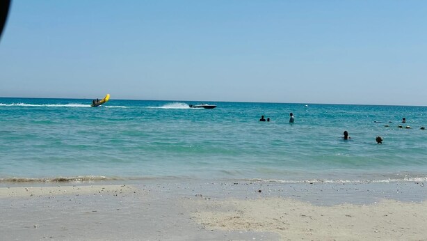 A beach with a clear sky, calm sea, and a few people swimming. - Spacious bright apartment 300 m from the beach - tourist area - wifi (Mahdia)