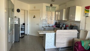 A compact kitchen with a refrigerator, microwave, and sink. There is a small dining area with a table and chairs. - Spacious bright apartment 300 m from the beach - tourist area - wifi (Mahdia)
