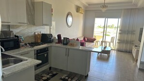 A modern kitchen with a central island, a dining area with a table and chairs, and a view of the outdoors through a sliding door. - Spacious bright apartment 300 m from the beach - tourist area - wifi (Mahdia)