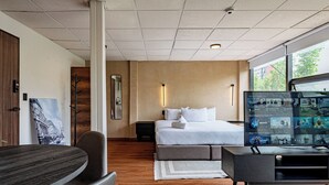 A modern hotel room with a bed, a TV displaying Apple TV content, a desk with a chair, and a large window offering a view of the outdoors. - VH  Loft moderno en Cibeles Roma Norte  169 (Ciudad de México)