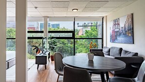 A modern meeting room with a round table, black chairs, and a large window offering a view of buildings and trees. - VH  Loft moderno en Cibeles Roma Norte  169 (Ciudad de México)