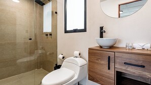 A modern bathroom with a glass-enclosed shower, a white toilet, and a wooden vanity with a bowl sink. - VH  Loft moderno en Cibeles Roma Norte  169 (Ciudad de México)