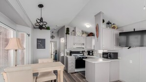 A compact kitchen with white cabinetry, a central island, a microwave, and a stove. - Updated 1-bedroom queen/ Free WiFi, AC Resort of Greenfield Village Mesa 55+ (Mesa)