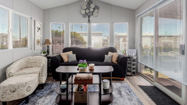 A living room with a black sofa, a patterned armchair, a coffee table, and a view of the city through large windows. - Updated 1-bedroom queen/ Free WiFi, AC Resort of Greenfield Village Mesa 55+ (Mesa)