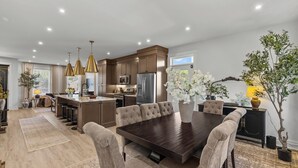 A spacious kitchen with modern appliances, a dining area with a large table and comfortable chairs, and a cozy seating area with a sofa and a coffee table.