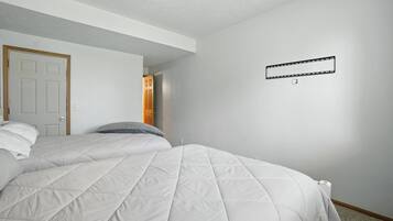 A bedroom with two beds, a door, and a light switch on the wall.