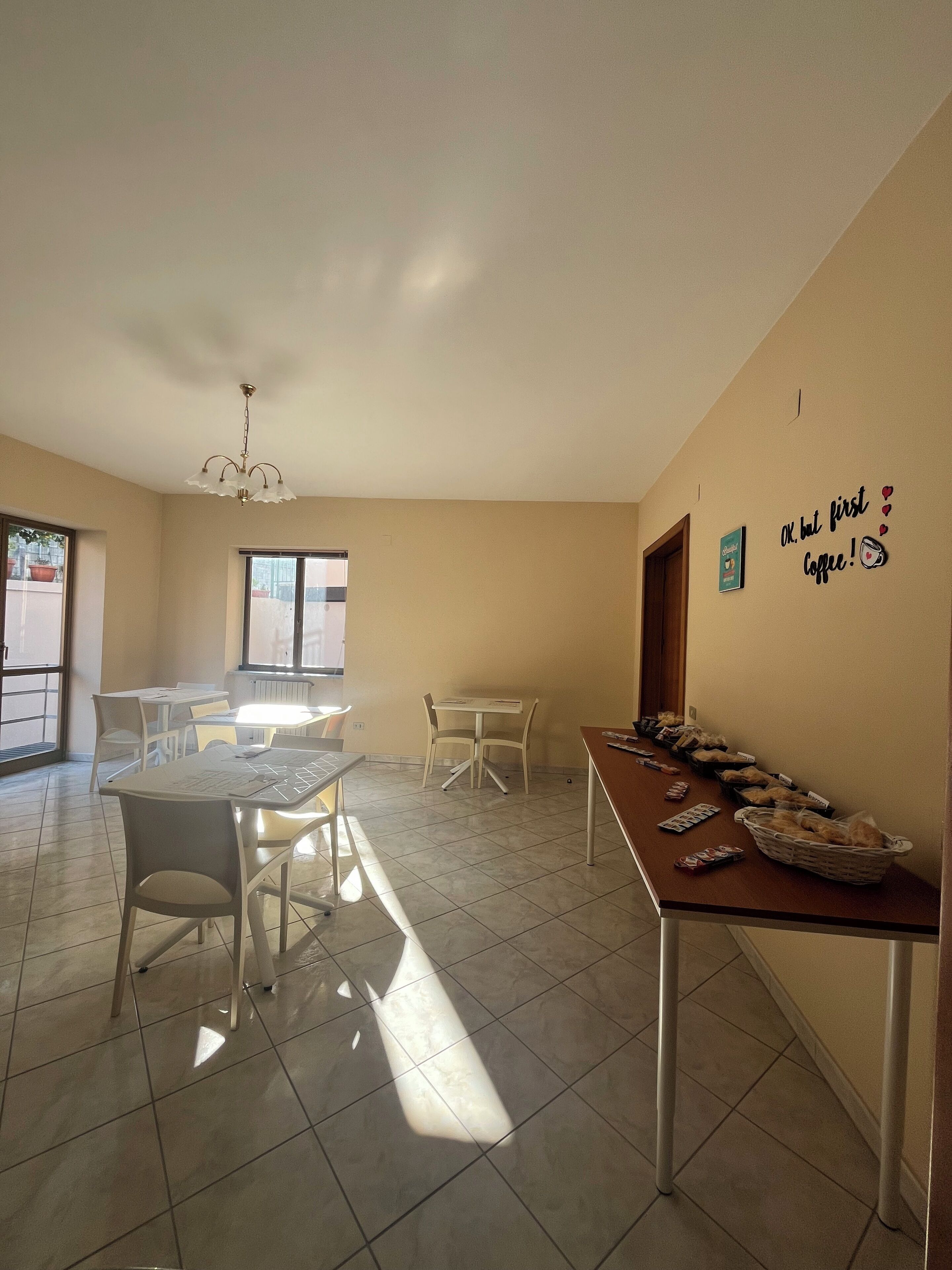 A spacious dining area with a long table, chairs, and a chandelier.