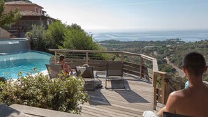 A poolside area with a wooden deck, lounge chairs, and a view of the sea. - F2 - Casina n° 5 - 1 Bedroom - Sea View (PORTO VECCHIO)