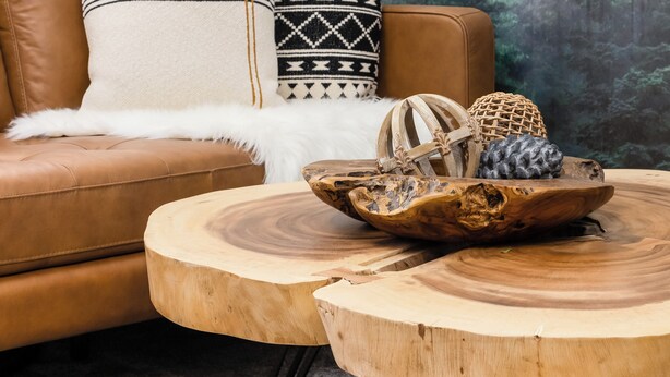 Ein gemütliches Wohnzimmer mit einem braunen Ledersofa, einem runden Holztisch und einer Wandmalerei von einem Wald.