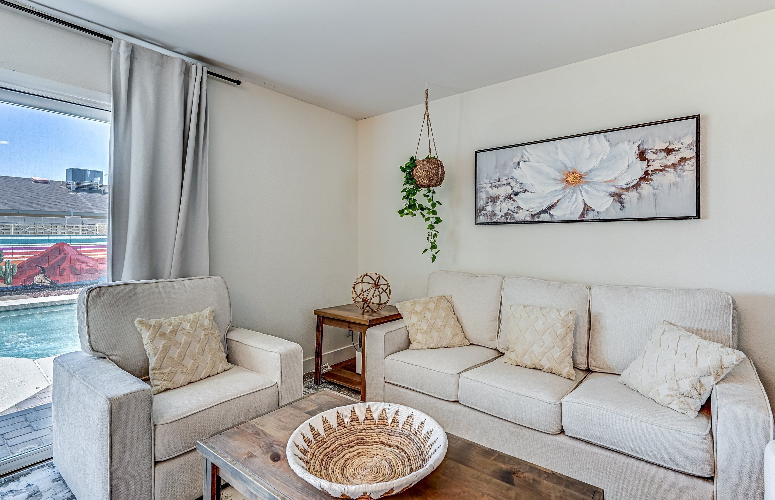 A modern living room with a beige sofa, a coffee table, and a painting of a flower.