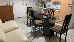 A compact kitchen with a dining table, chairs, and a small cabinet. - Superior Two-room Apartment – ALH Hotel Digitale (Taranto)
