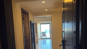 A hallway with a view to a balcony, a door with a metal handle, and a tiled floor. - Grand Solmar Resort and Spa in Cabo! Come celebrate Christmas! (Cabo San Lucas)