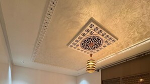 A bedroom with two beds, a decorative ceiling, and a window with blinds. - Charming 4-bedroom villa in enchanting مراكش with WiFi, AC.pool (مراكش)