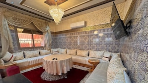 A luxurious living room with a round coffee table, a sofa set, and a chandelier. - Charming 4-bedroom villa in enchanting مراكش with WiFi, AC.pool (مراكش)