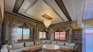 A luxurious room with a large seating area, a chandelier, and intricate wall and ceiling designs. - Charming 4-bedroom villa in enchanting مراكش with WiFi, AC.pool (مراكش)
