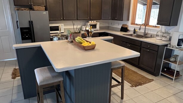 A modern kitchen with dark cabinets, a central island, and a built-in oven. - Private Oasis Close to the City (LaFayette)
