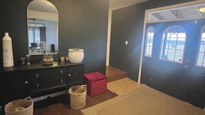 A bedroom with a dark wall, a wooden dresser, a mirror, a red ottoman, and a large rug. - Private Oasis Close to the City (LaFayette)