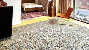 Une chambre d’hôtel avec un lit, une chaise, une grande fenêtre et un tapis à motifs.