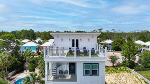 Una casa de dos pisos con balcón, piscina y vista a viviendas vecinas.