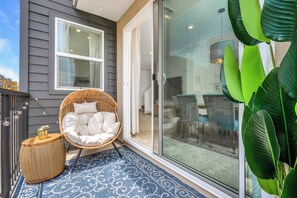 A balcony with a wicker chair, a patterned rug, and a potted plant. - Multi-Level Corner Home in Prime Gated Community (Los Angeles)