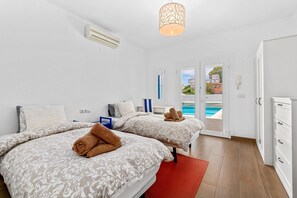 Habitación de hotel con dos camas, un tapete rojo, una lámpara en el techo y vista a una piscina.