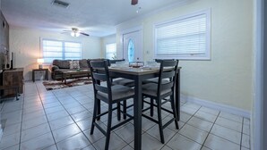 Un comedor con una mesa, sillas, ventilador de techo y una ventana con persianas.