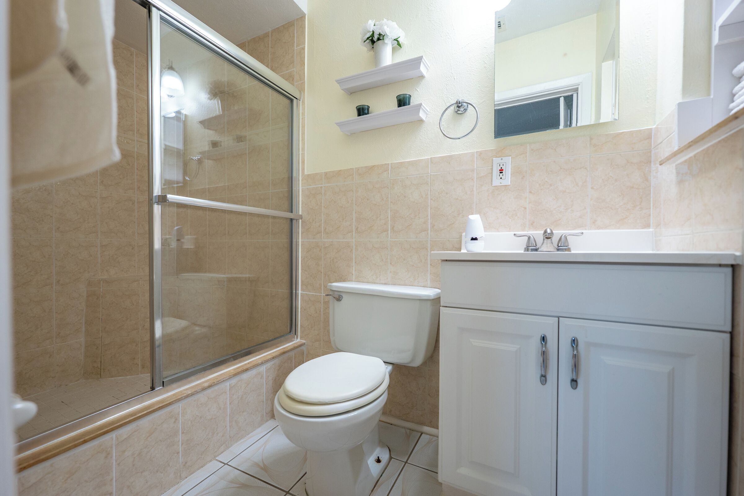 Een badkamer met een douchecabine, toilet en een wastafel met spiegel erboven.