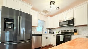 Une cuisine moderne dotée d’appareils électroménagers en acier inoxydable, de meubles blancs et d  ’un plan de travail en bois.